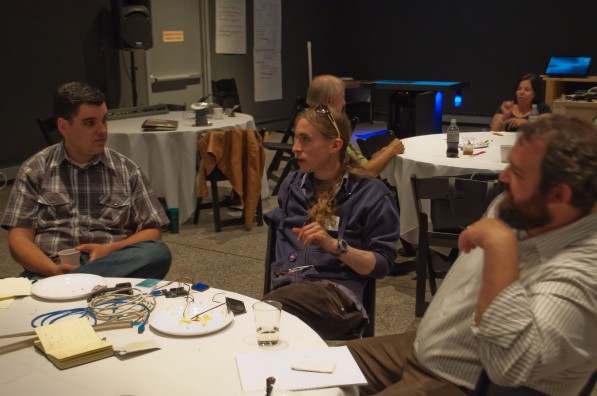 Photo of CMME workshop participants sitting at a table, talking to each other